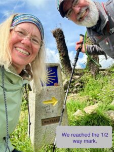 Philip and Laura at the Camino de Santiago halfway marker along a grassy stretch of the trail.