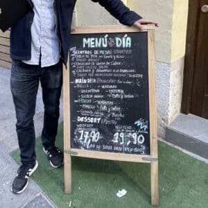Handwritten menú del día board in Valencia showing paella and fideuà options with weekday and weekend prices.
